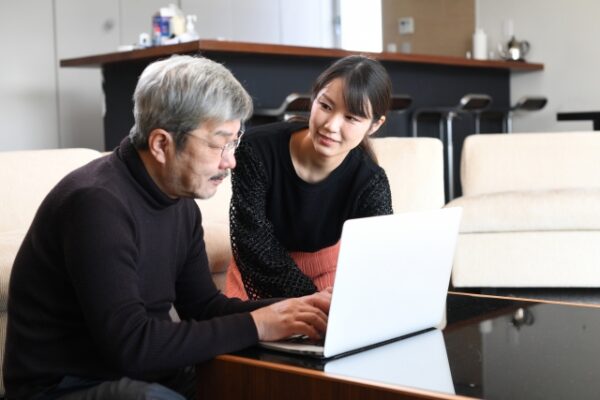 秘書にサポートされながら画像ファイル共有をする葬儀社の経営者