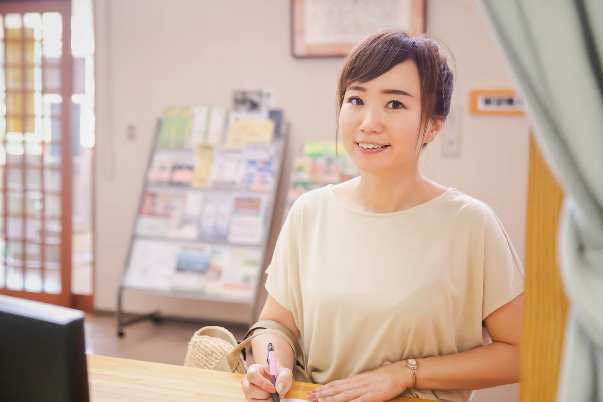 介護施設受付窓口で葬儀社のイベント開催の案内を見る女性